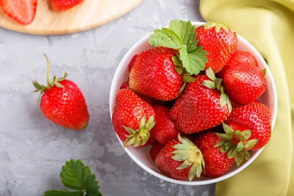 fresh and juicy red strawberries in a white bowl on top of a table