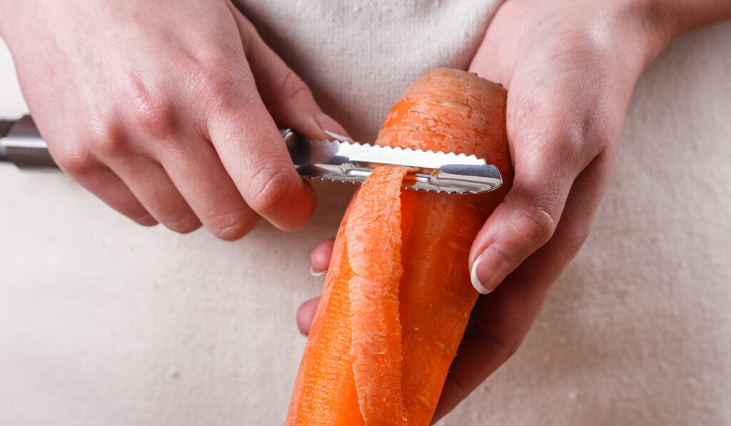 woman in apron peeling a carrot