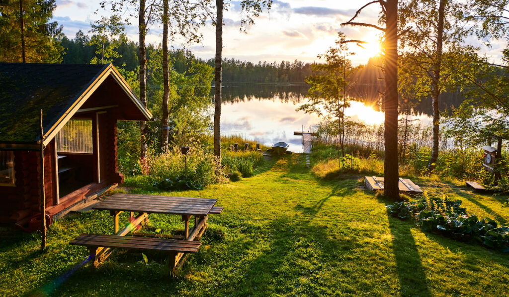 Lake view in Finland with sunrise, wooden table and cottage