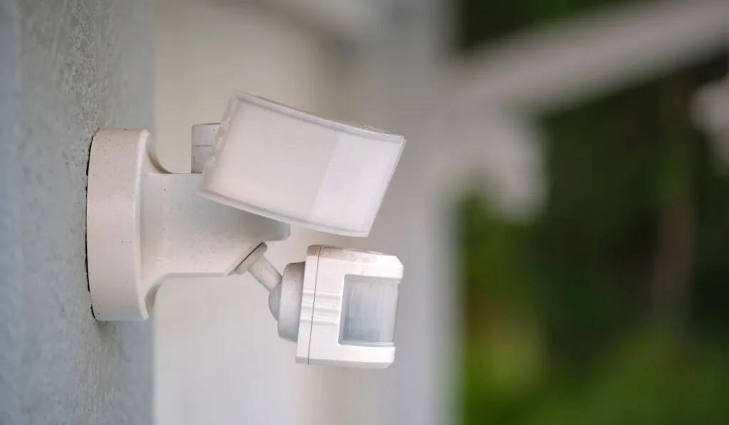 White Motion sensor light detector mounted on exterior wall 