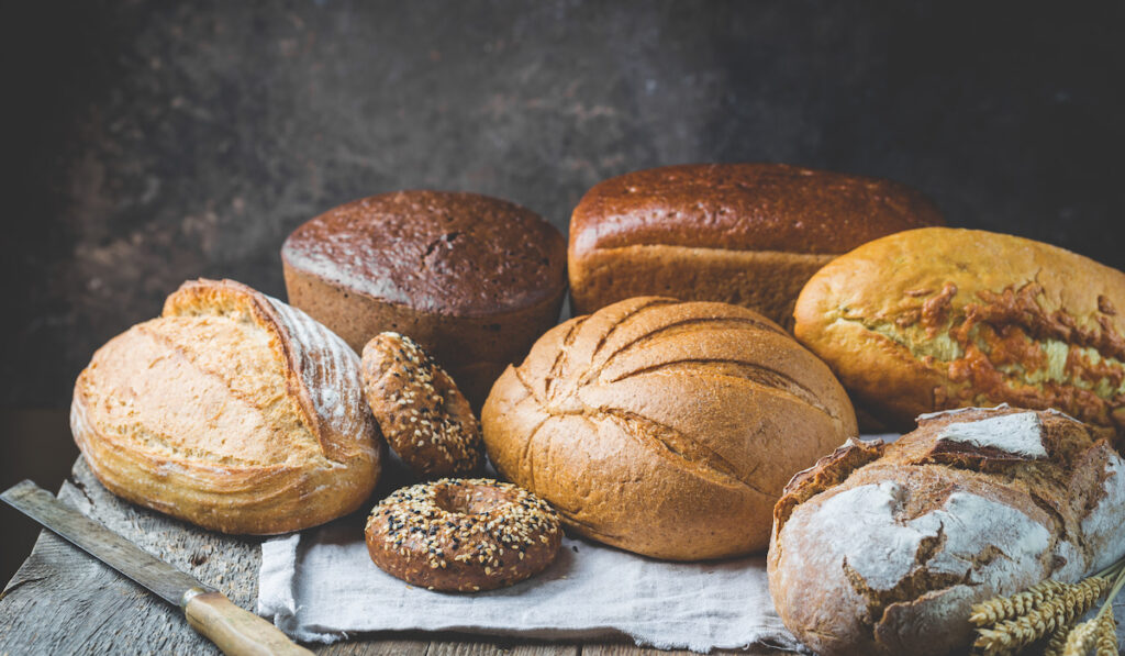 Assortment of fresh baked bread and buns on wooden table background

