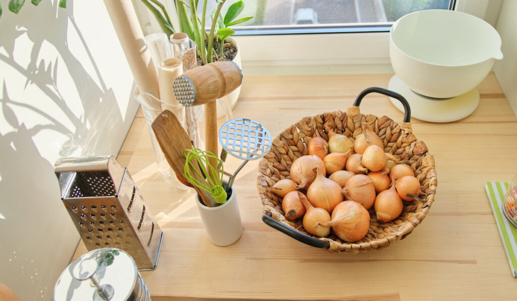 Basket with golden onions on wooden table in kitchen