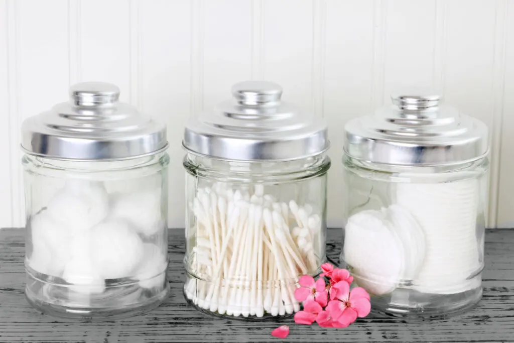 Empty candle jars storing cottons and buds in the bathroom 