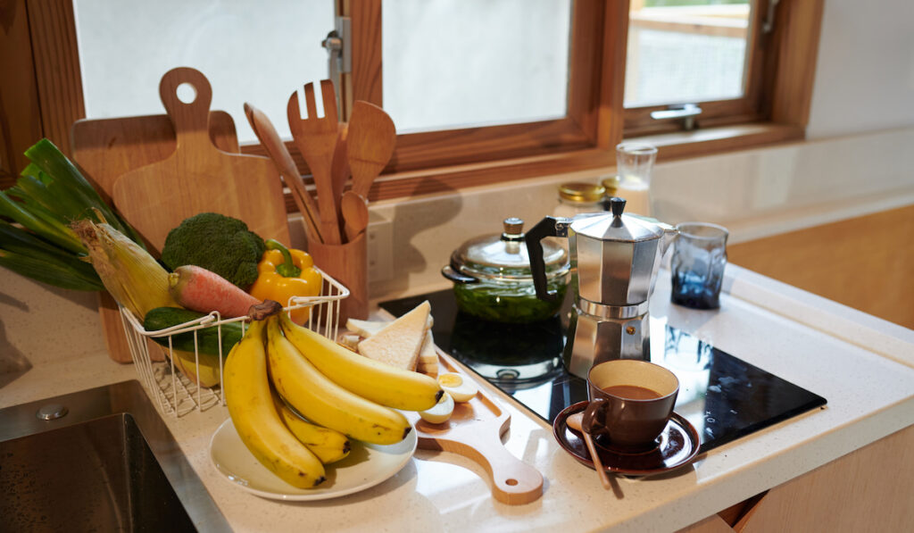 Fresh bananas, vegetables and coffee cup on kitchen counter