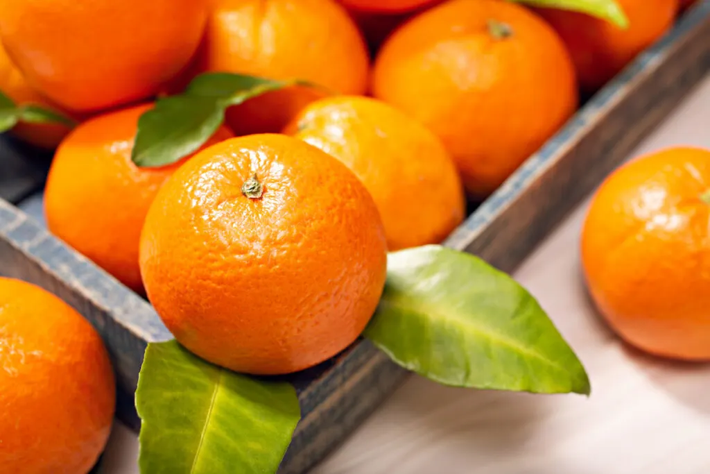Fresh orange fruits on a wooden tray on top of a table