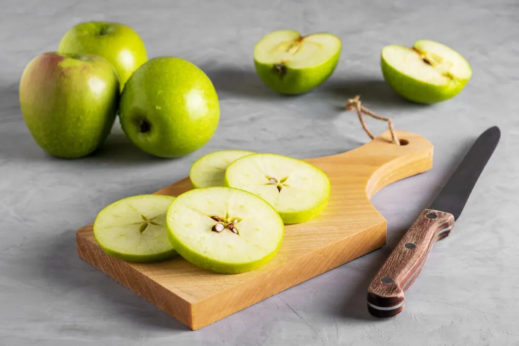 Fresly cut sliced green apples on a board on top of a marbled table