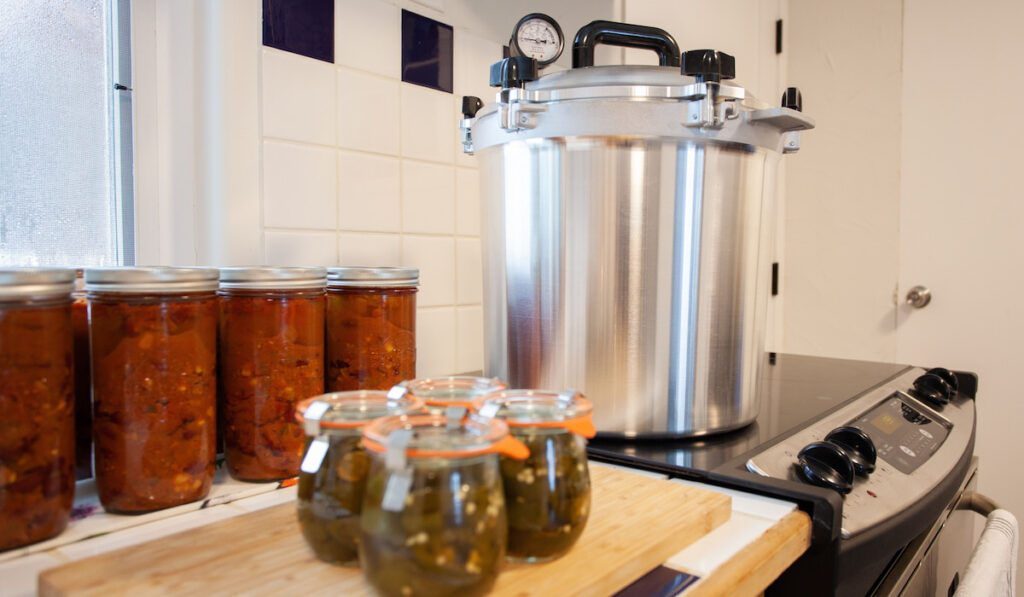 Home Canning jalapenos in jars and a batch of chili with a pressure cooker