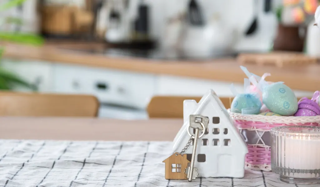 Key to house of cozy home with Easter decor with rabbit and eggs on table of kitchen
