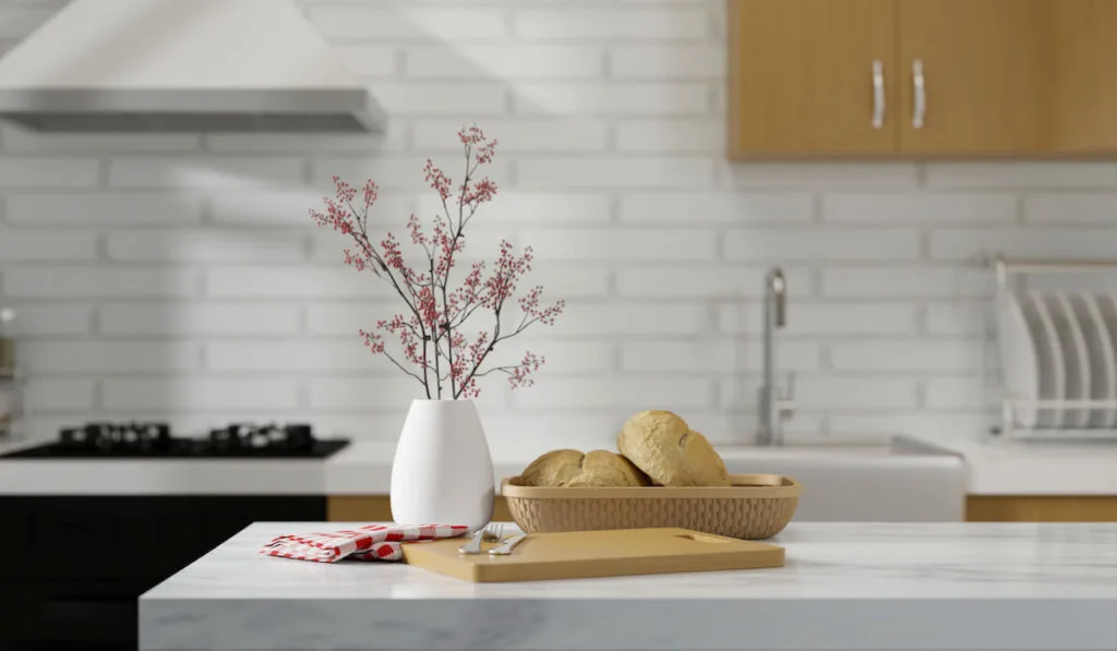 Marble kitchen counter island with a bread basket, flower in a vase