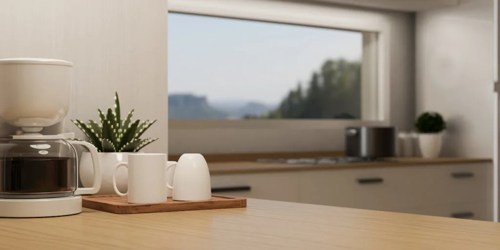 Modern coffee maker and mug tray are on wooden kitchen countertop