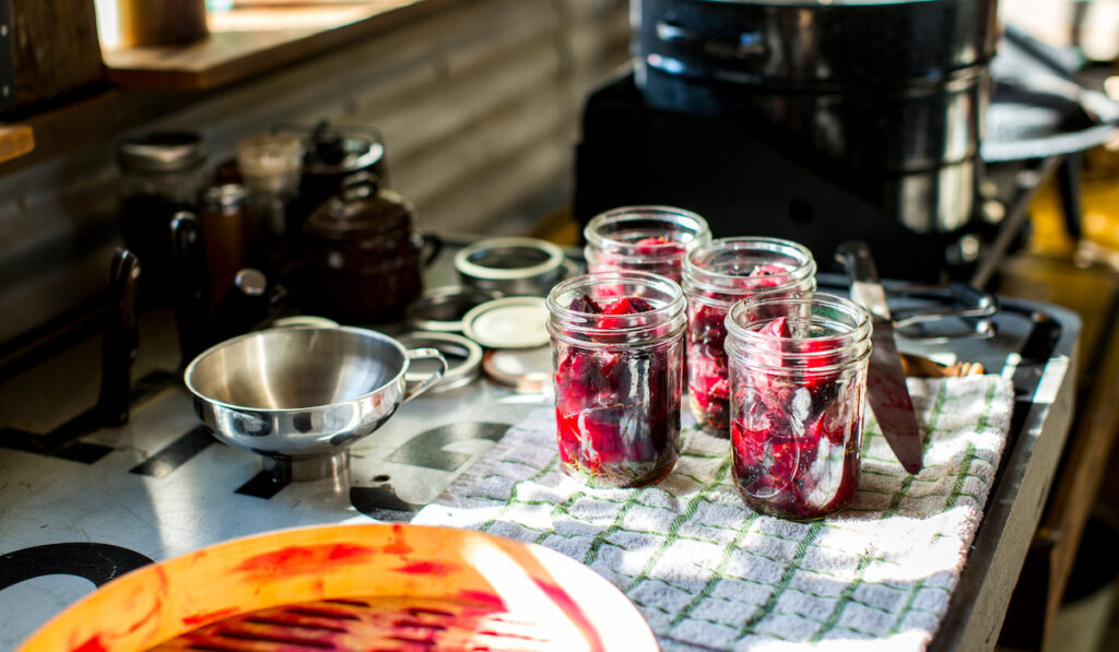 Preserves jars of beetroot on tea towel in kitchen
