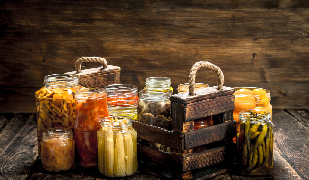 Preserves mushrooms and vegetables in a box. On a wooden background