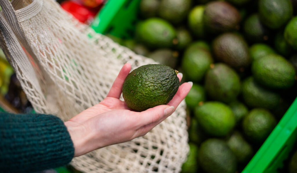 Woman choosing avocados in the supermarket