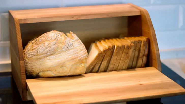 wooden bread box with bread on the counter top