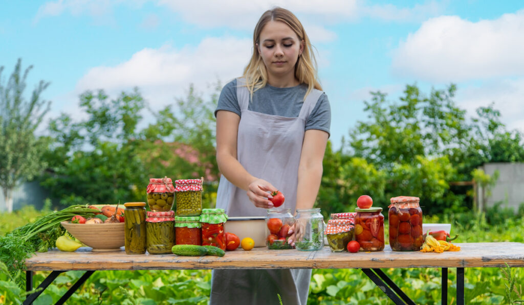 Young woman preserves different vegetable in the garden