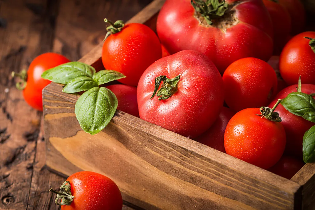 fresh tomatoes in a wooden crate on top of a table