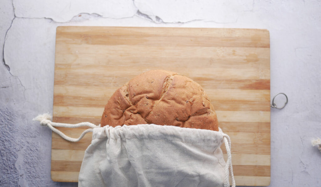 freshly baked bread coming out from linen bread bag on a wooden chopping board