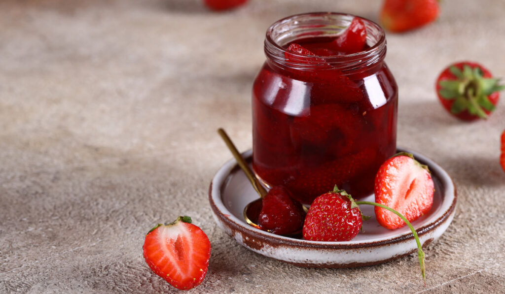 natural organic strawberry jam in a jar and fresh strawberries on the ground