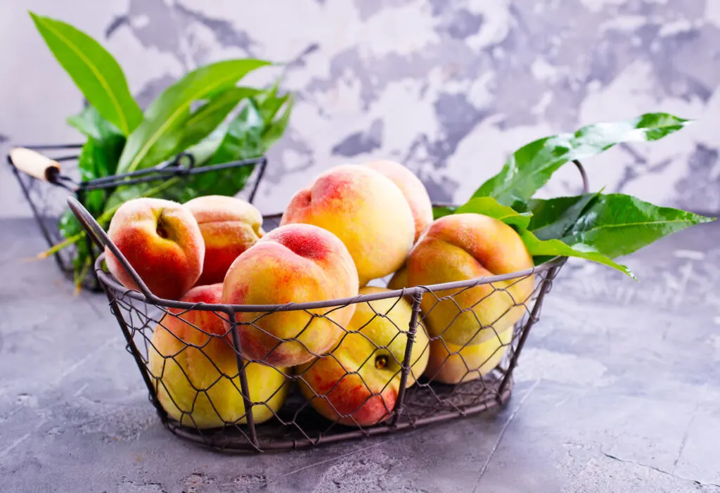 peaches in a steel basket on a countertop