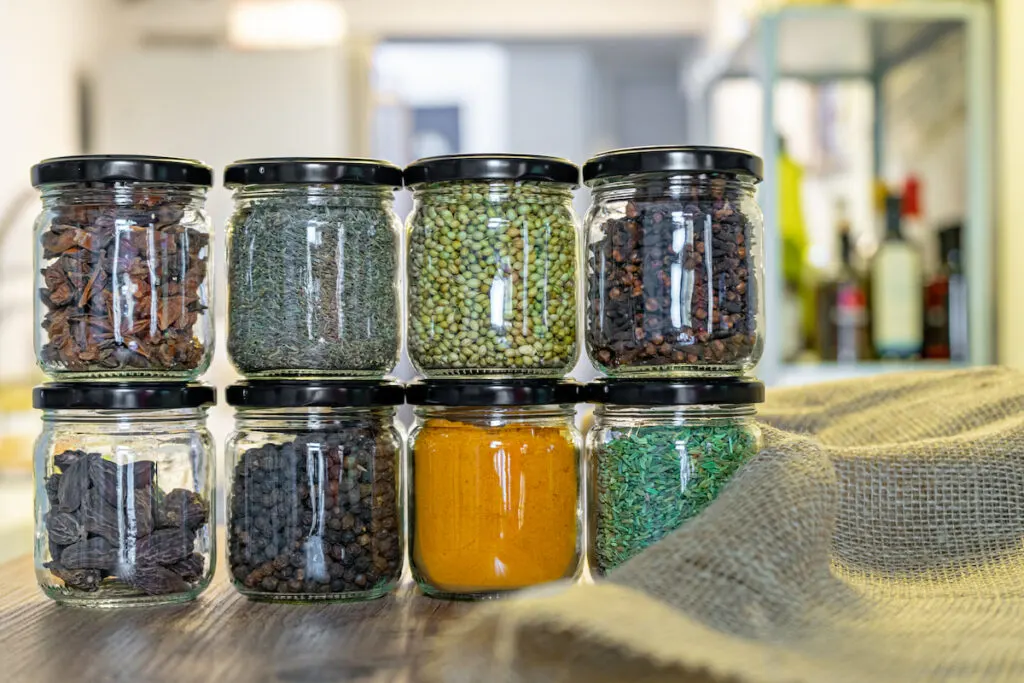 spices and herbs inside an empty candle jars on the table