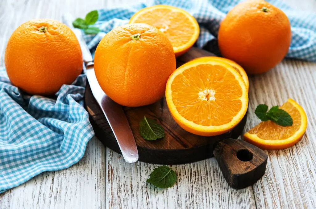 whole and sliced orange on a board on a table