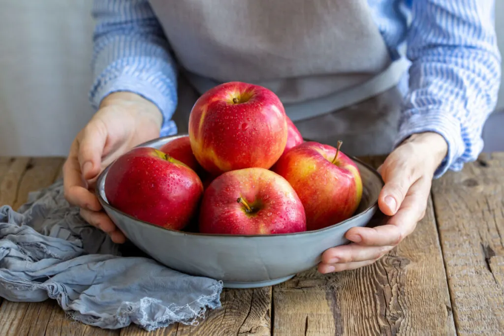 woman holding a bowl with washed red apples to be dried