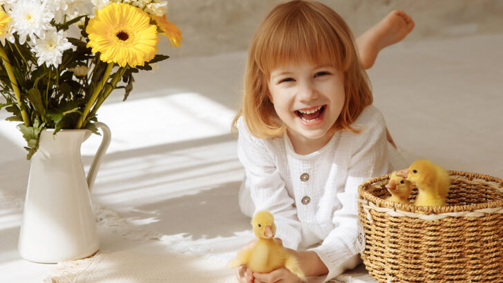 cheerful child holds a live duck in his hands