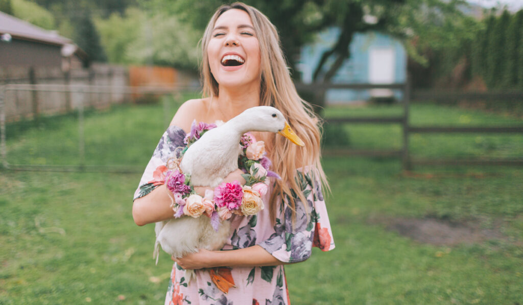 A woman laughing while holding a duck in the Spring
