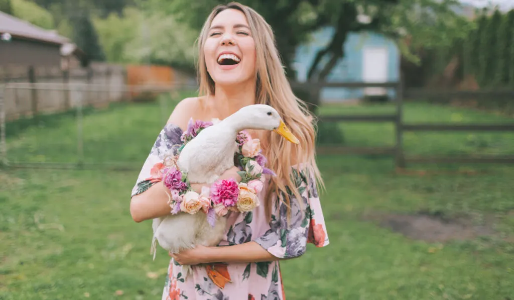 A woman laughing while holding a duck in the Spring
