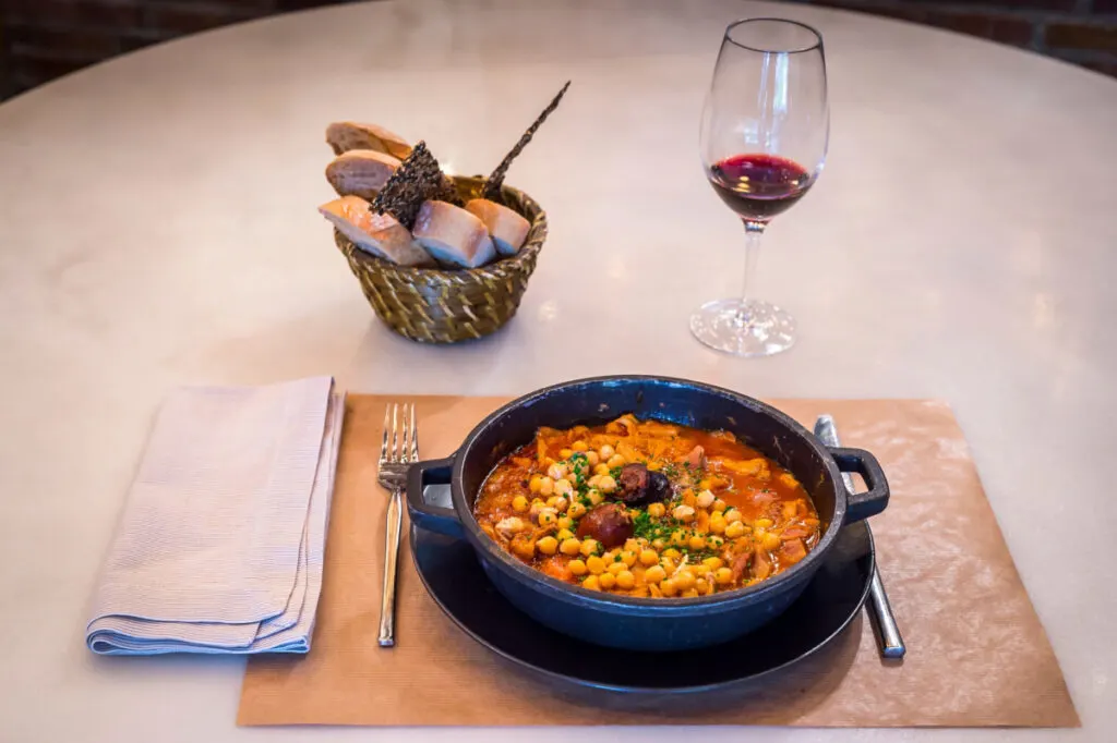 Chorizo and Chickpea Soup in a bowl with bread and wine