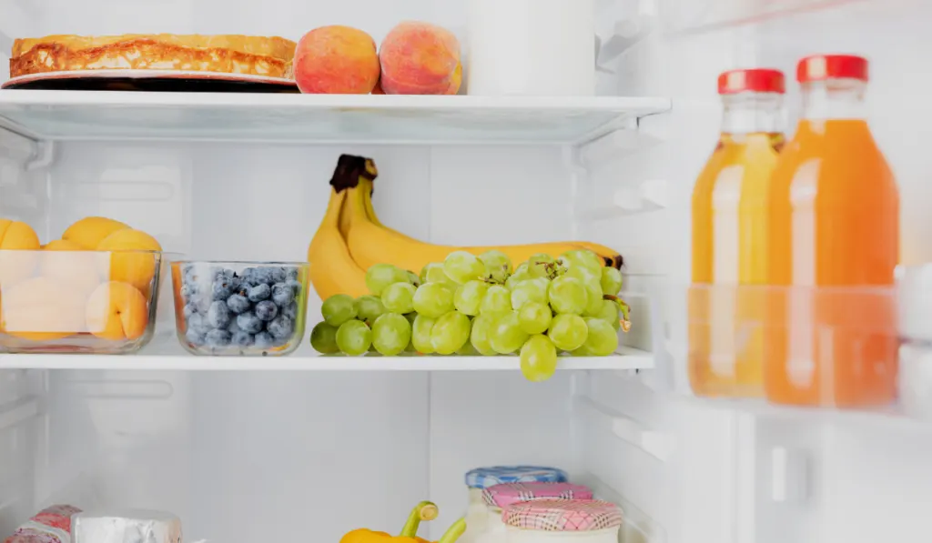 Open fridge or refrigerator door filled with fresh fruits