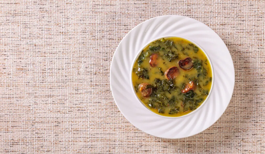 Portuguese potato and kale green soup with Chorizo Sausage in bowl on linen cloth