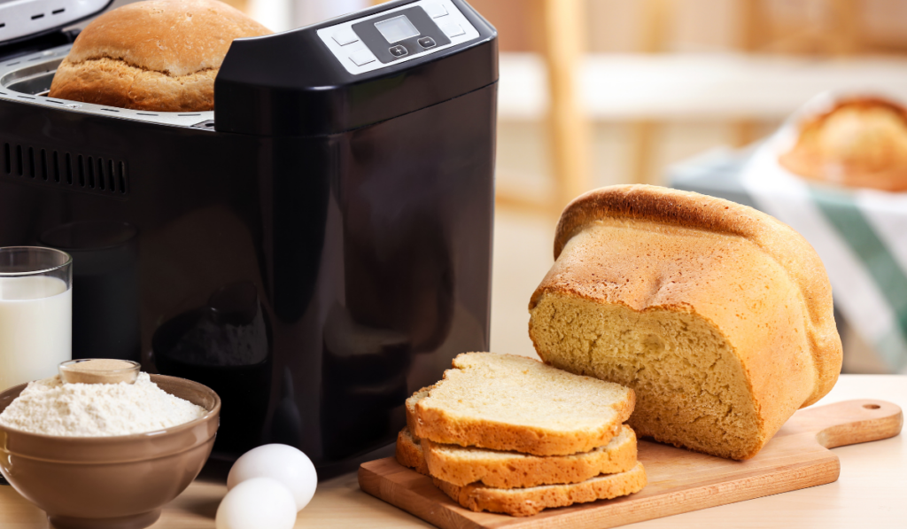 Tasty sliced loaf and bread machine on table
