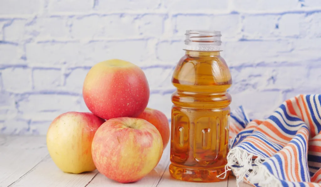 fresh apples and bottle of juice on table
